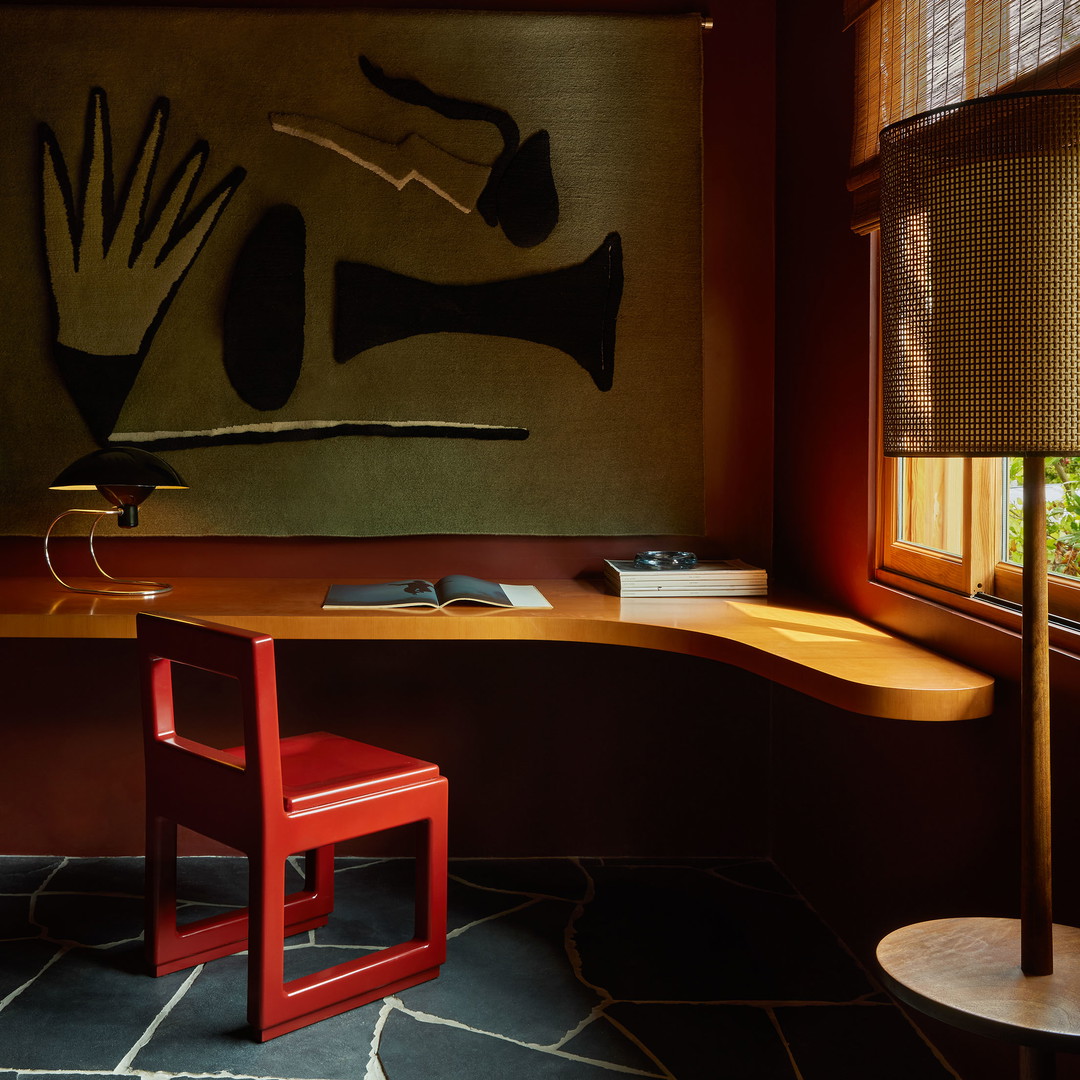 a desk with a red chair and a painting on the wall