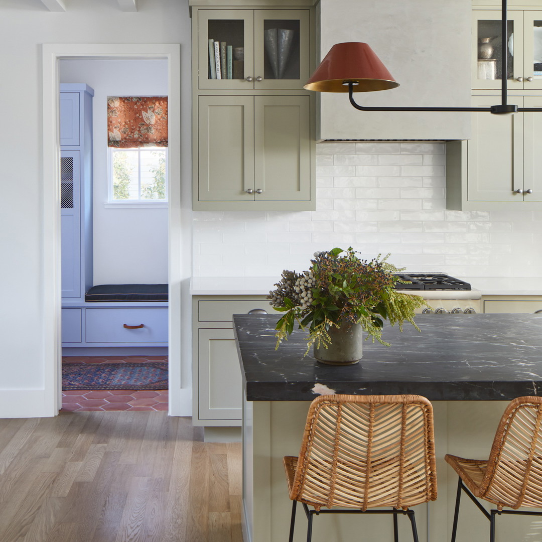 a kitchen with a black counter top and wooden chairs