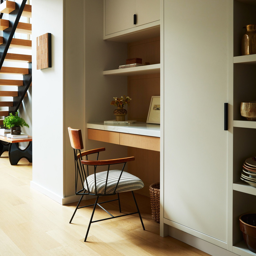 a chair sitting in front of a desk under a stair case