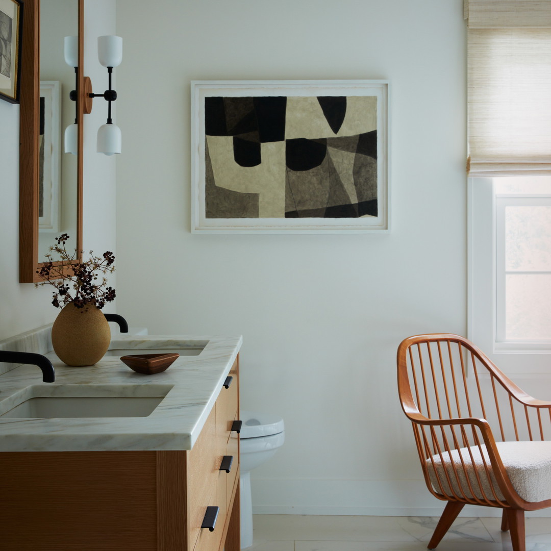 a bathroom with a chair and a painting on the wall