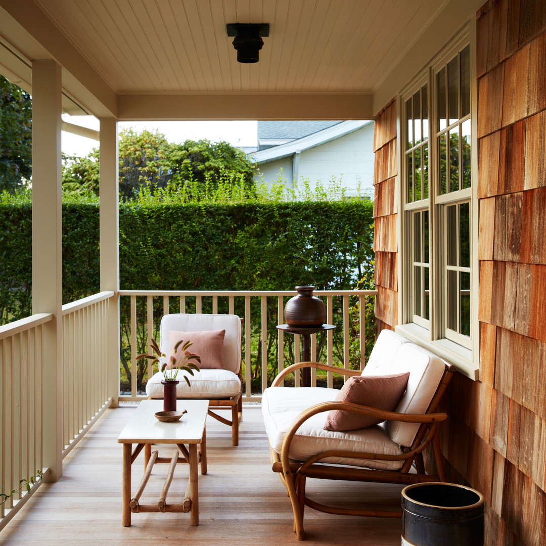 a wooden porch with two chairs and a coffee table