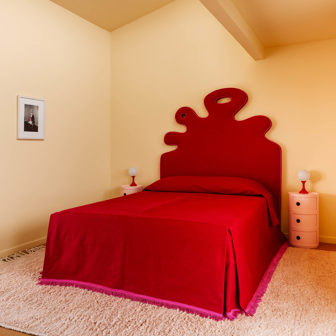 a bedroom with a red bed and white carpet