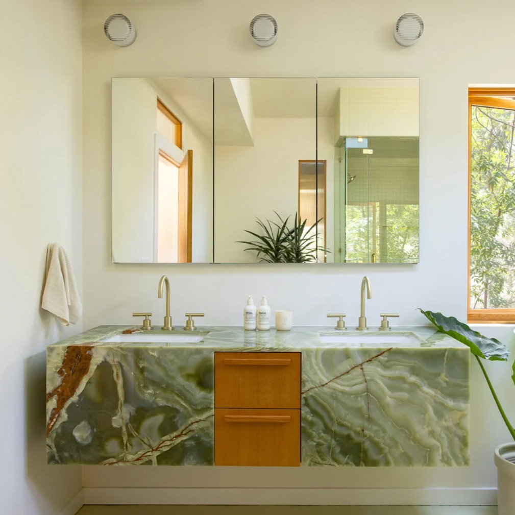 a bathroom with a sink, mirror and a plant