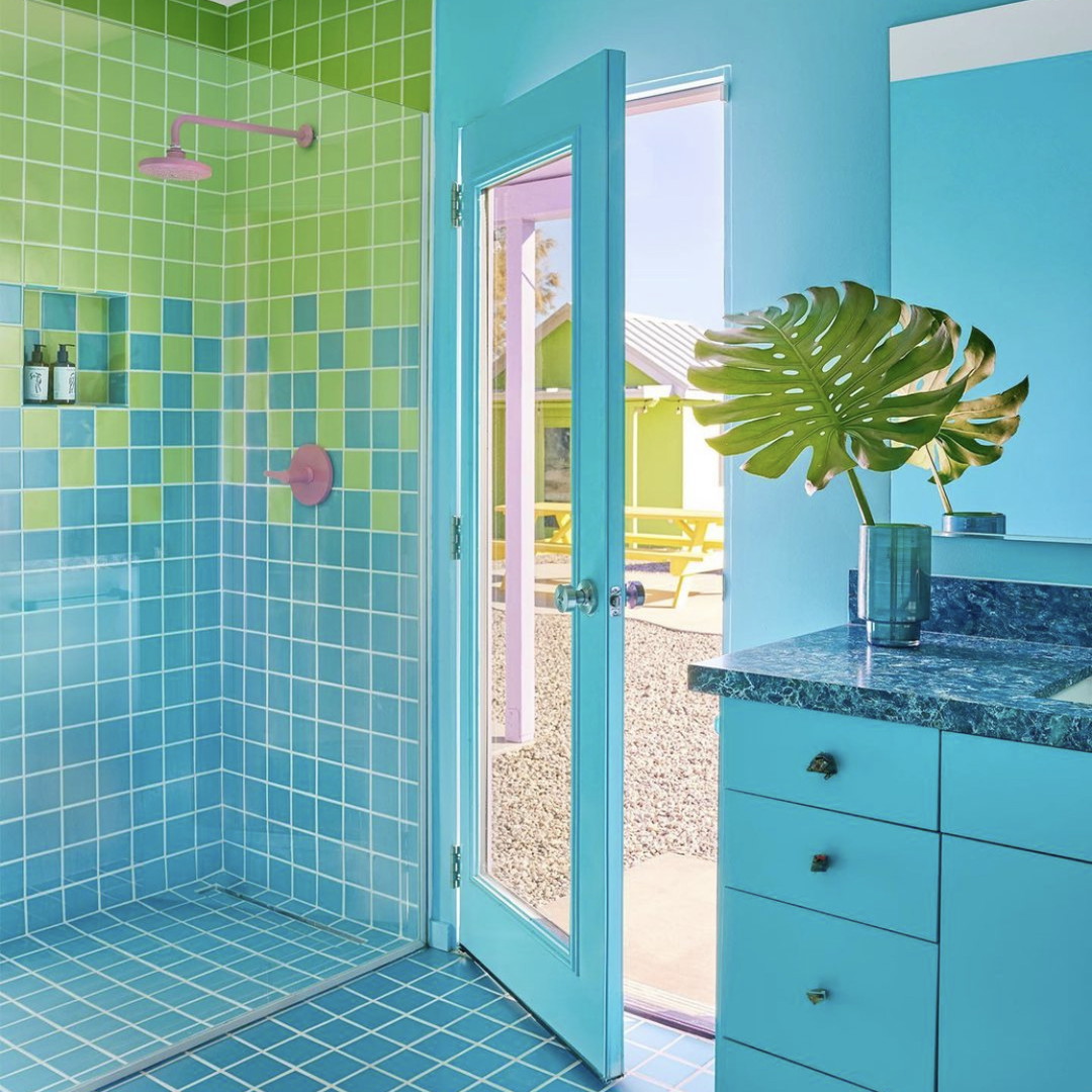 a bathroom with blue and green tiles and a potted plant