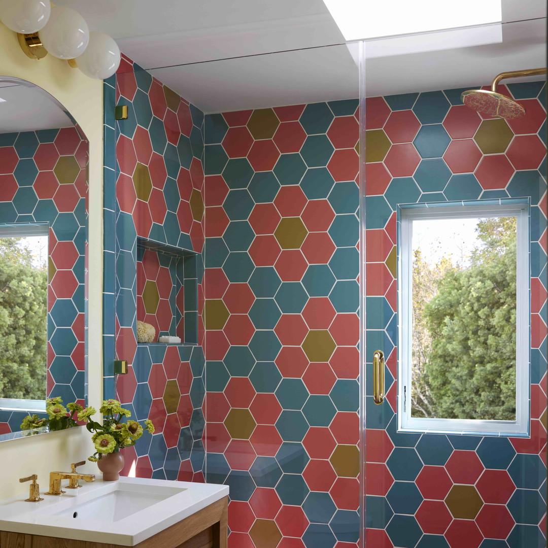 a bathroom with a colorful tiled wall and a wooden vanity