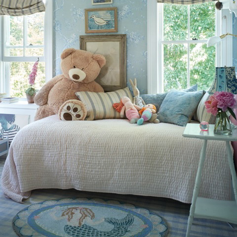 a teddy bear sitting on top of a bed in a bedroom