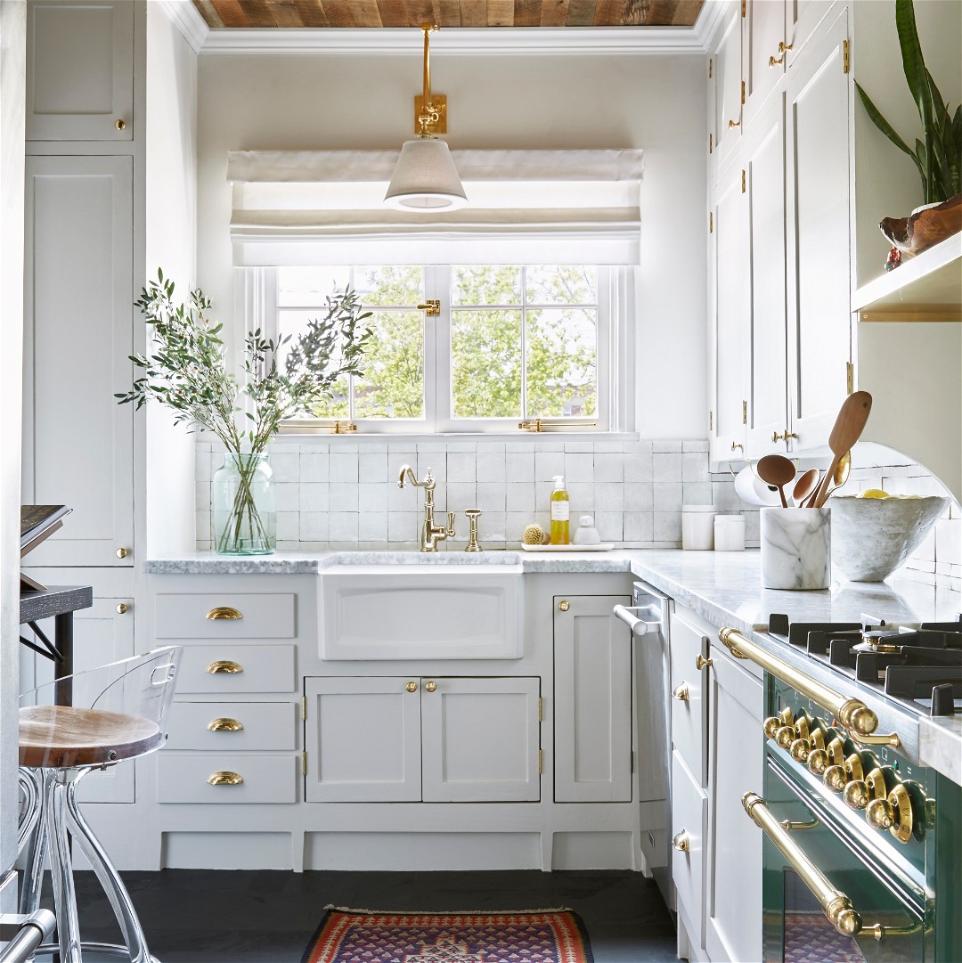 a kitchen with white cabinets and gold trim