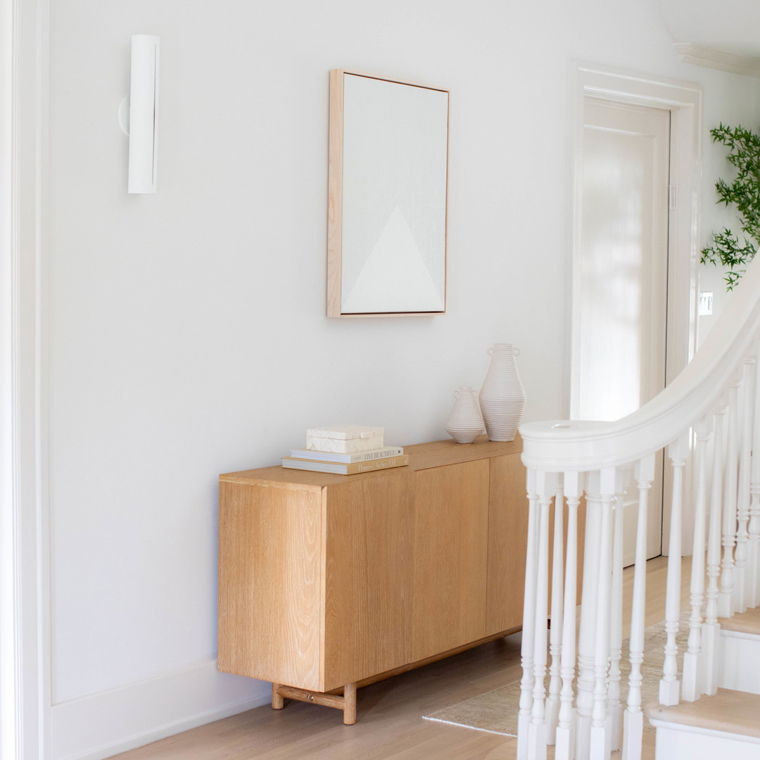 a white room with a wooden cabinet and a mirror on the wall