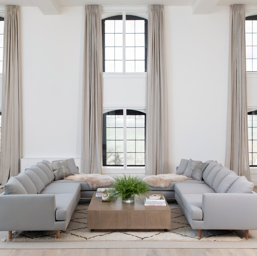 a living room filled with furniture and large windows