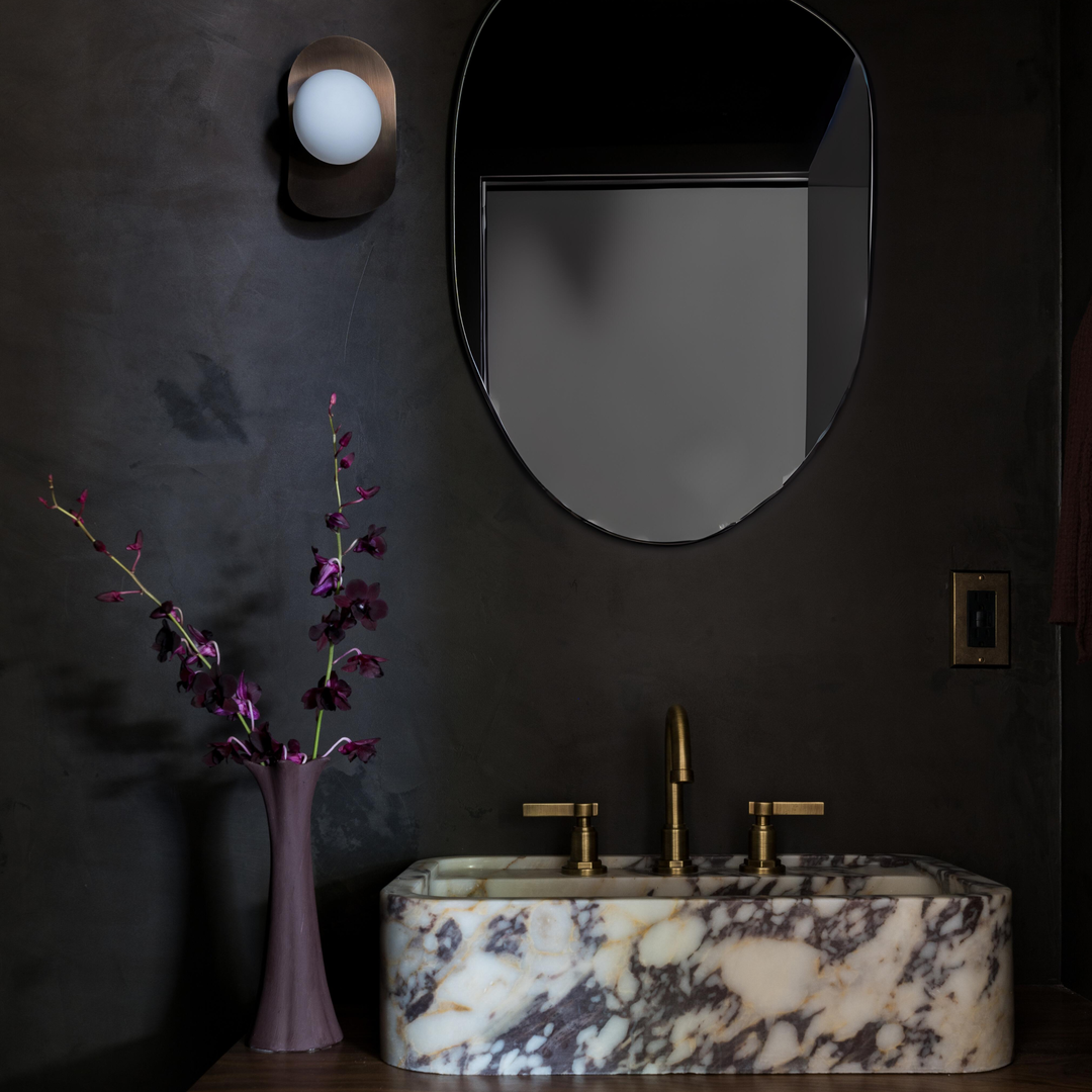 a bathroom with a marble sink and a round mirror