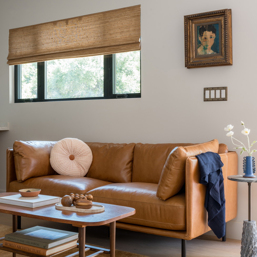 a living room with a brown leather couch and coffee table