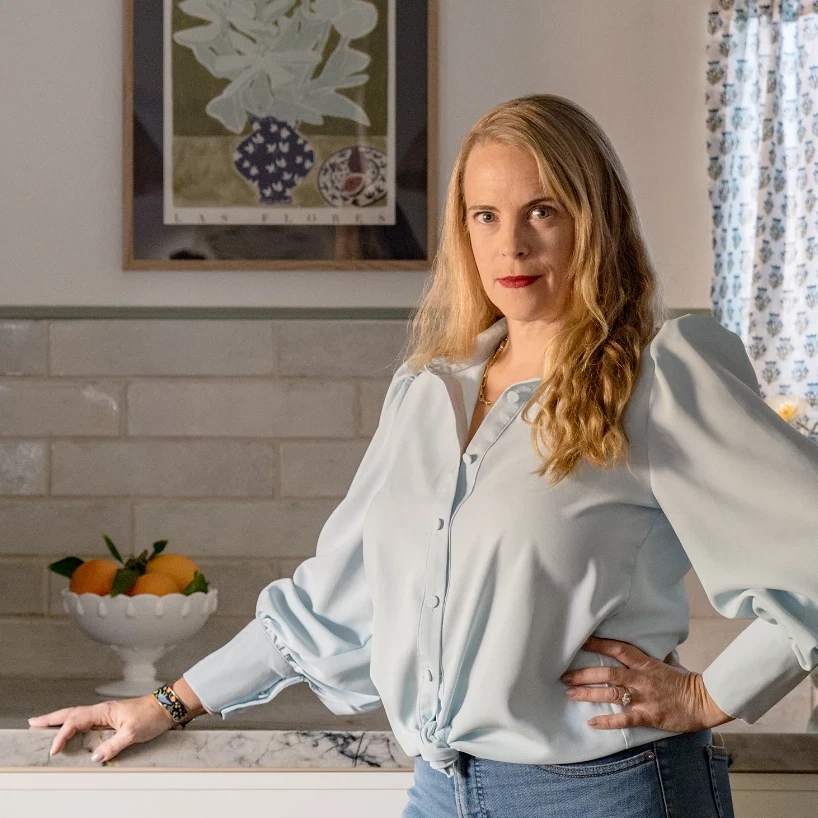 a woman standing in a kitchen next to a bowl of fruit