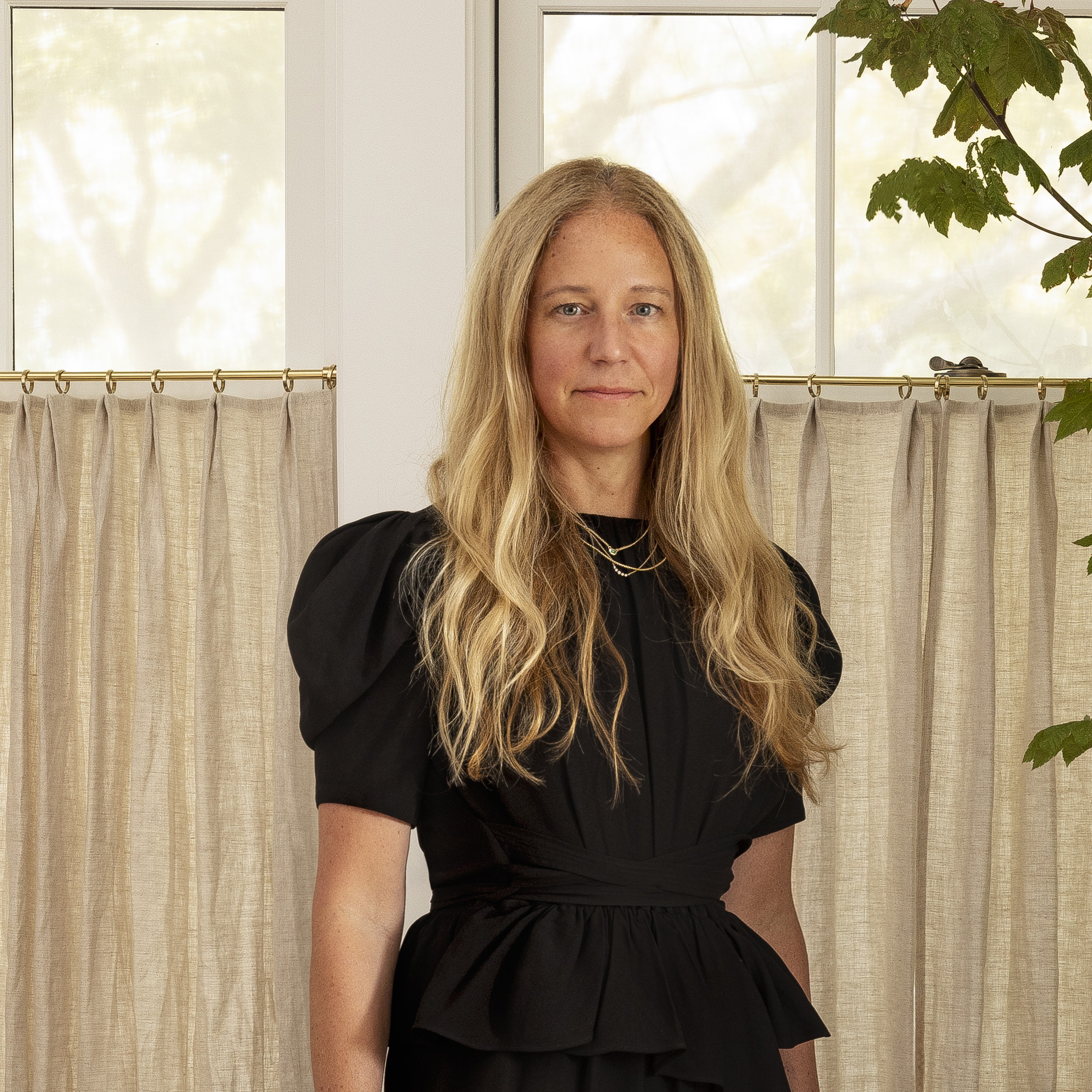 a woman standing in front of a window in a living room