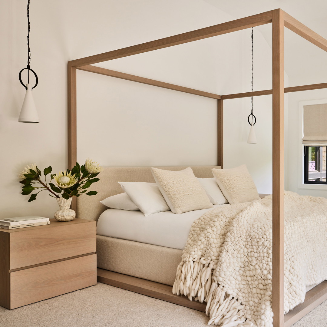 a bedroom with a four poster bed and white walls