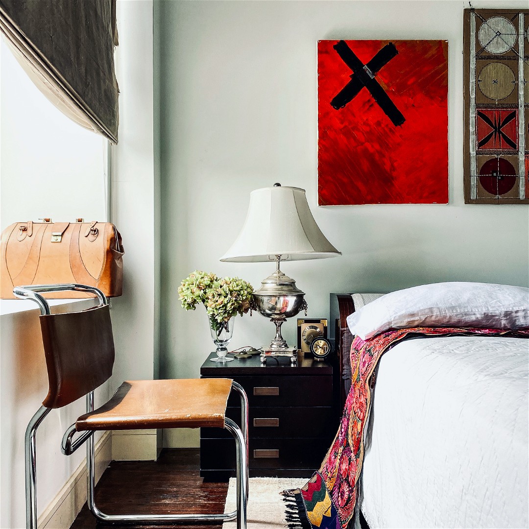 a bedroom with a bed, chair and a painting on the wall