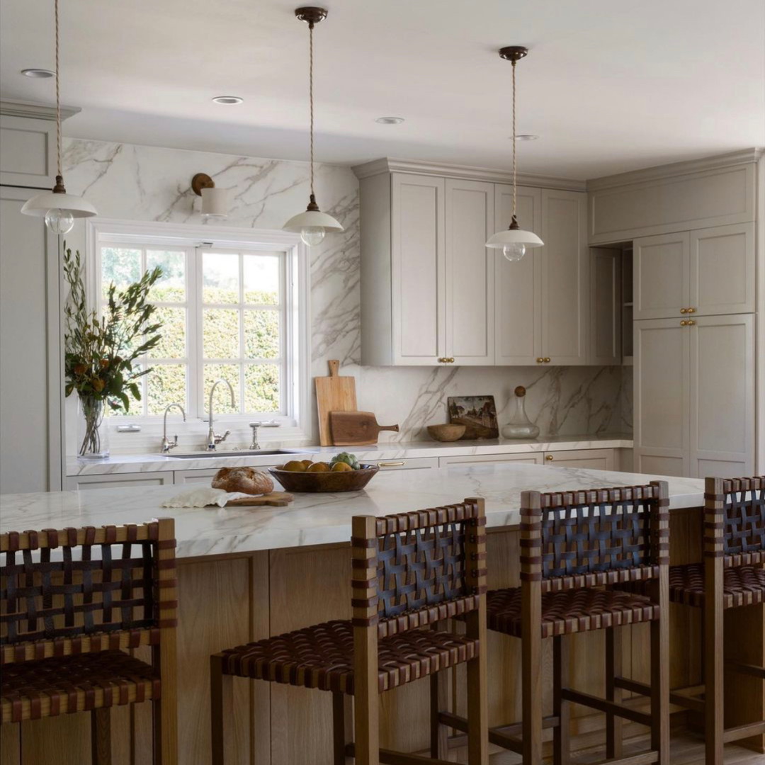 a kitchen with a marble counter top and wooden chairs