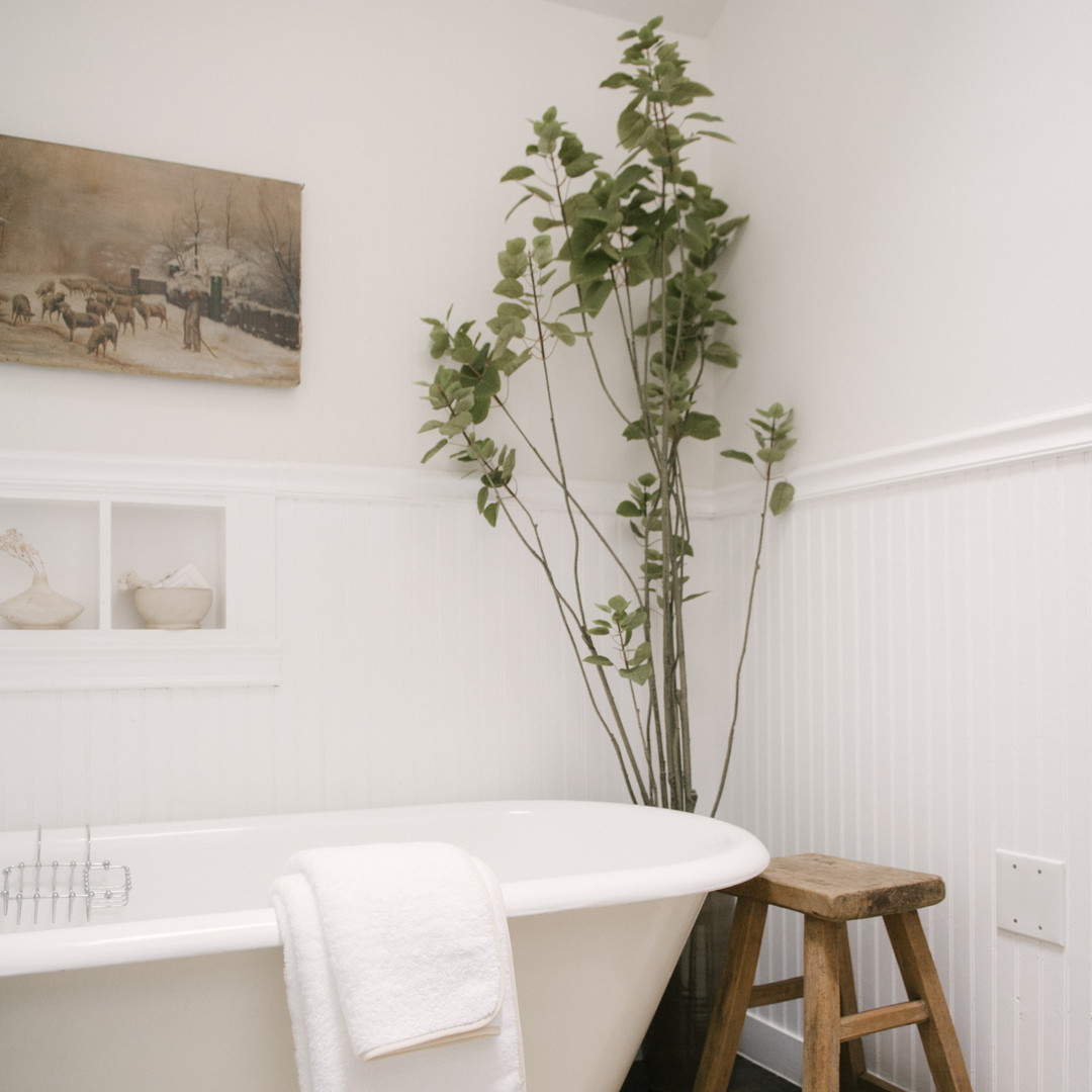 a white bath tub sitting next to a wooden stool