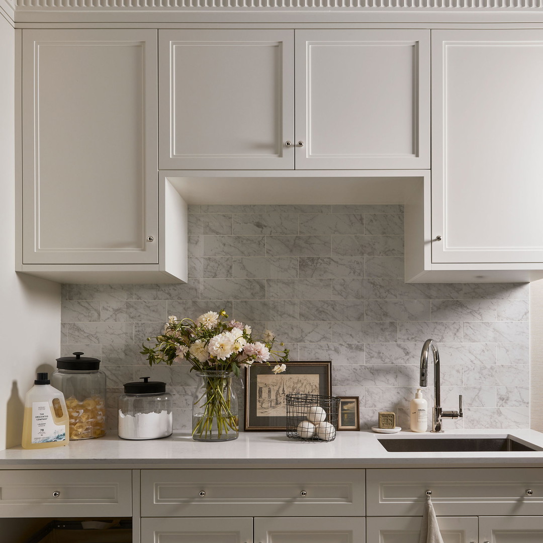 a kitchen with white cabinets and marble counter tops