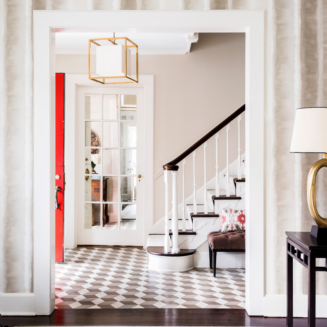 a foyer with a checkered floor and a red door