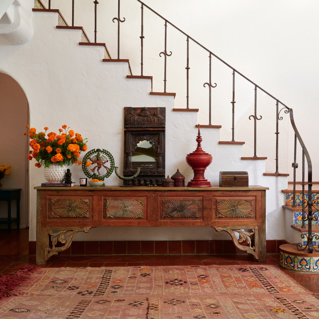 a foyer with a rug, vases and a staircase