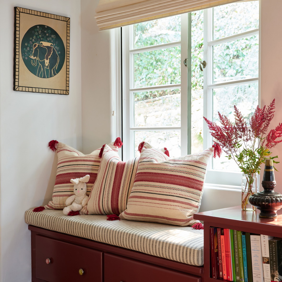 a window seat with pillows and a vase of flowers