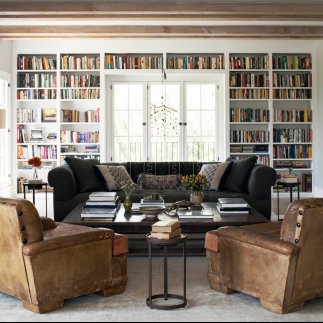 a living room filled with lots of books and furniture