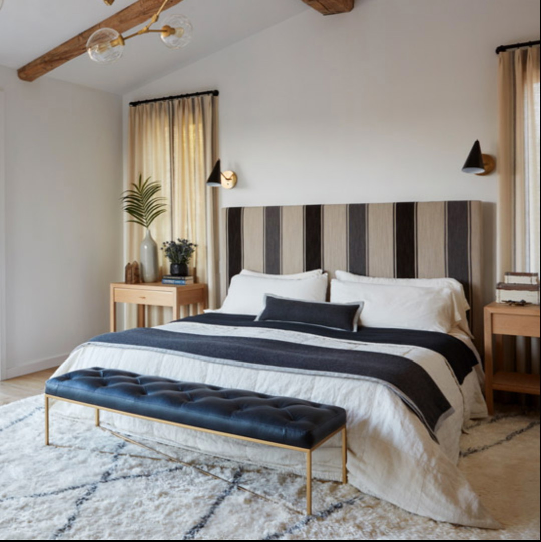 a bedroom with a large bed and a black and white striped headboard