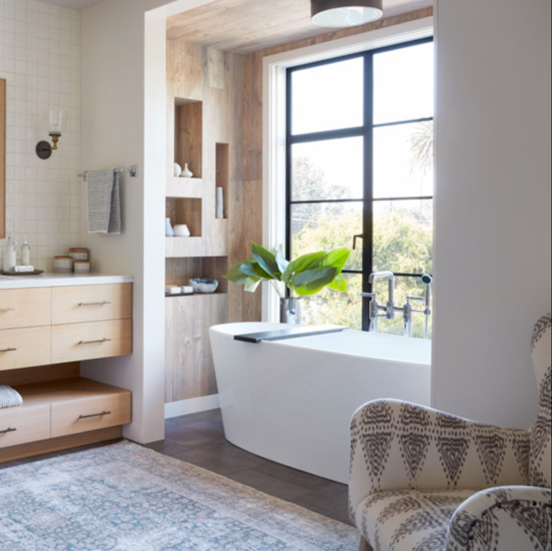 a bath room with a tub a chair and a window