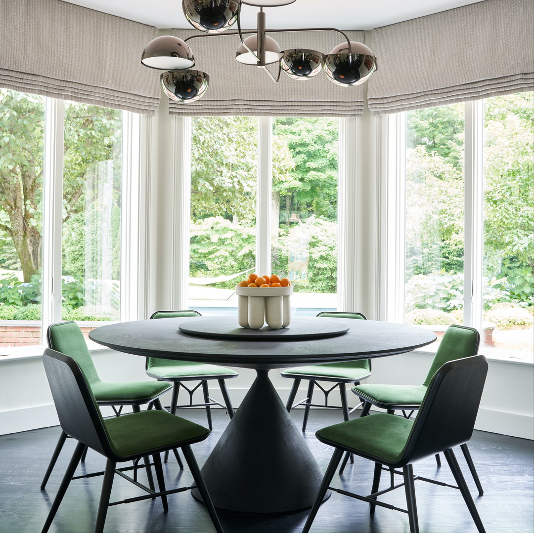 a dining room with a round table surrounded by green chairs