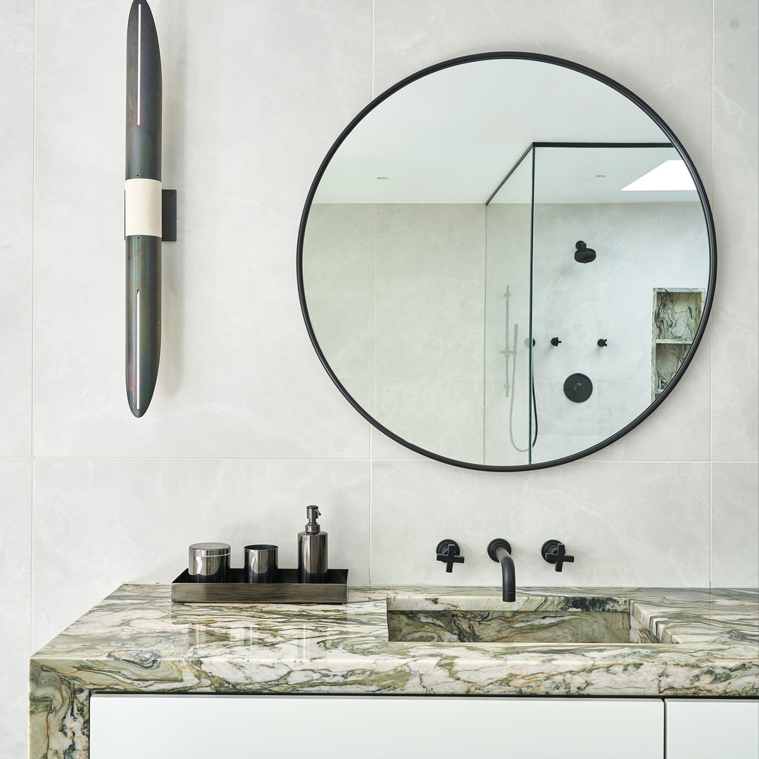 a bathroom vanity with a round mirror above it