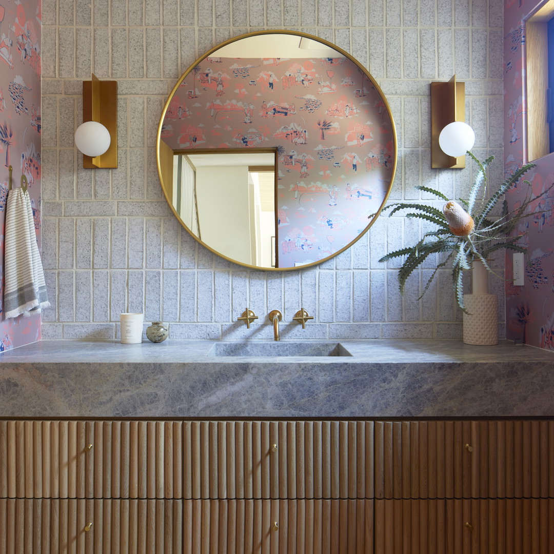 a bathroom vanity with a round mirror above it