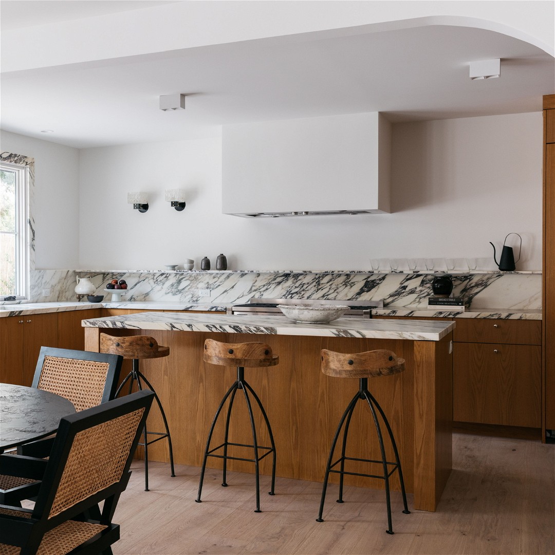 a kitchen with a marble counter top and wooden chairs