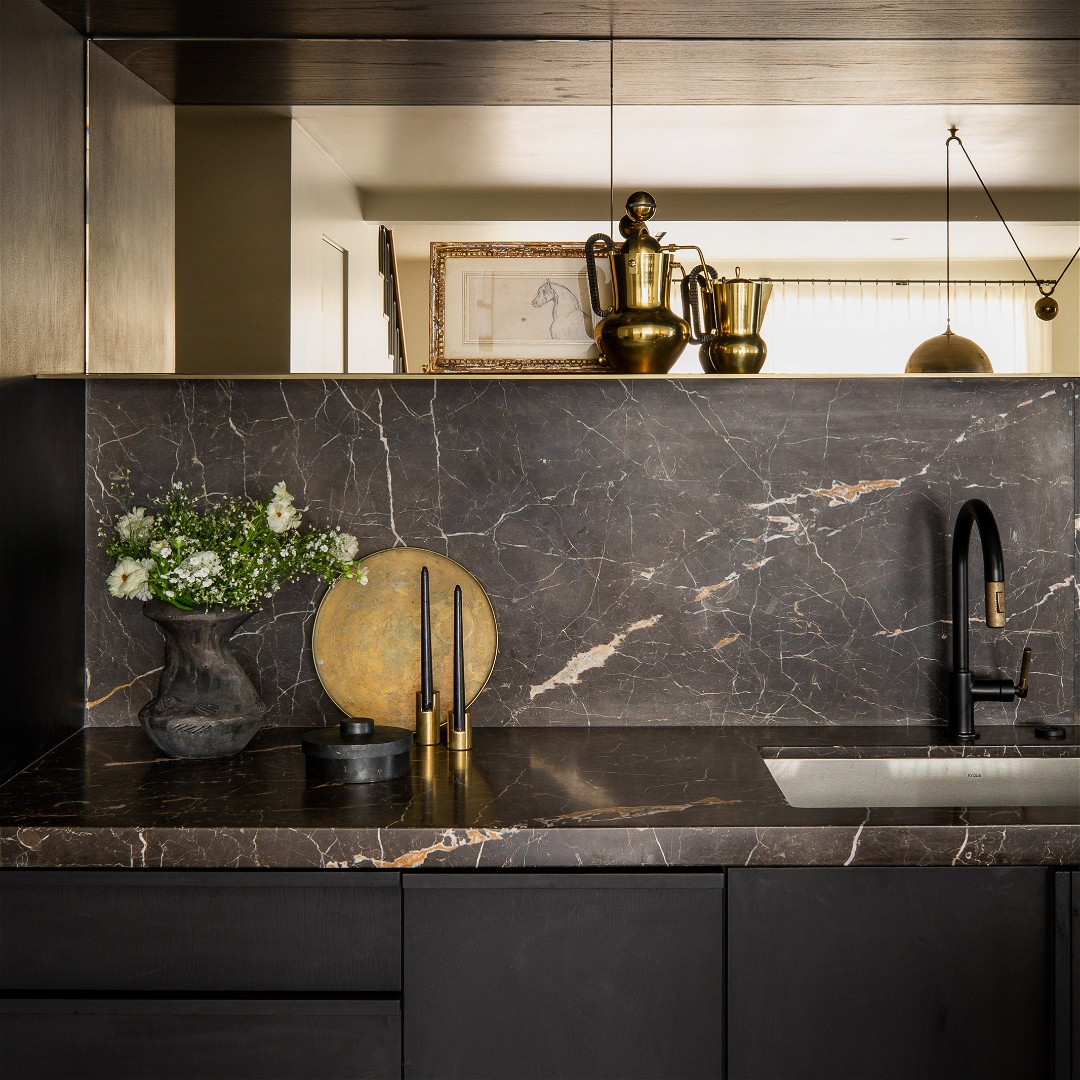 a kitchen with a marble counter top and black cabinets