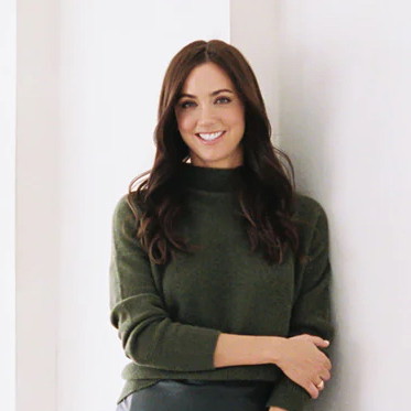 a woman leaning against a wall with her arms crossed