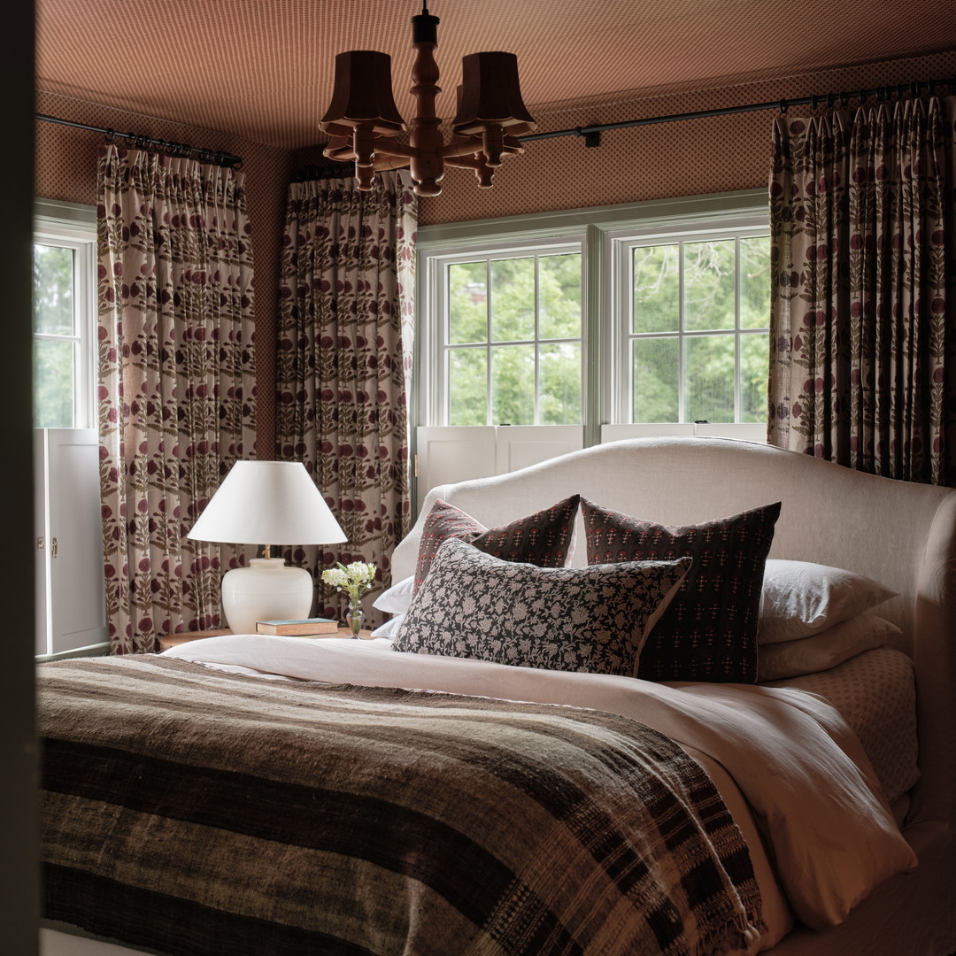 a bedroom with a bed, lamps, and windows