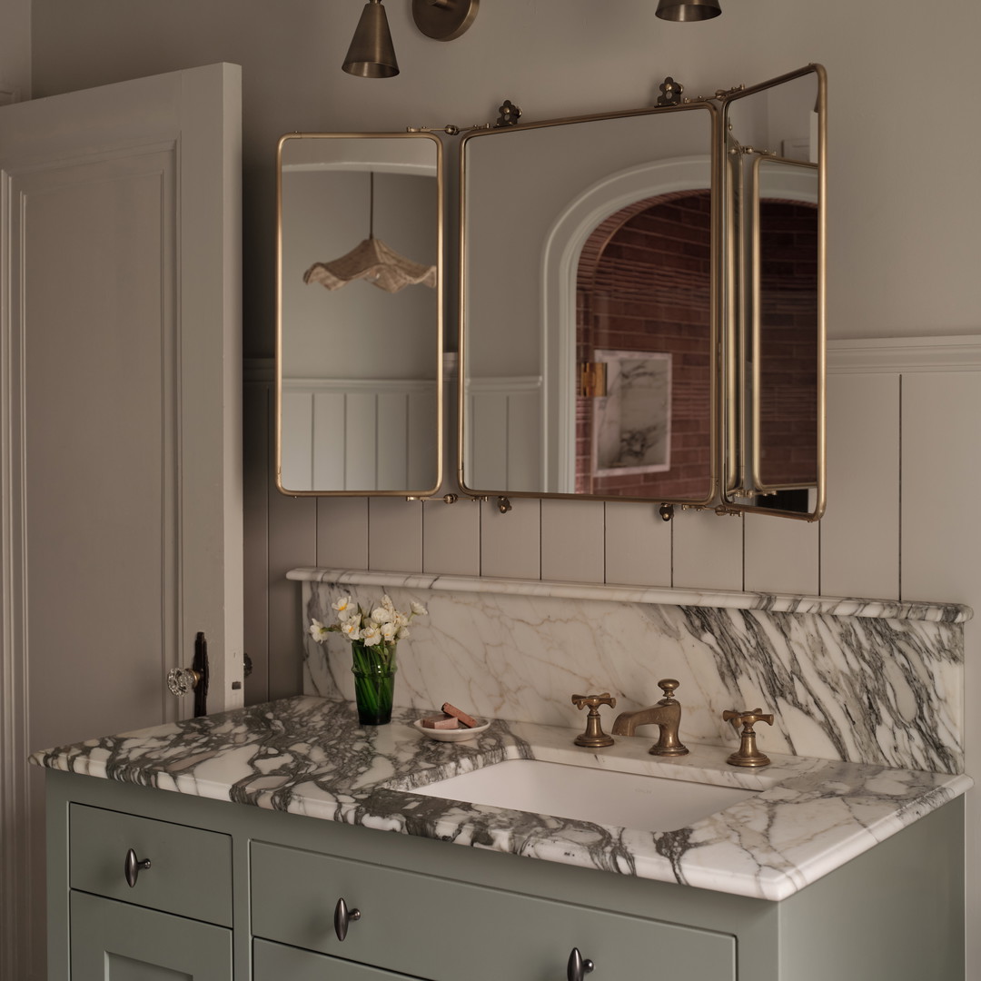 a bathroom with a marble counter top and two mirrors
