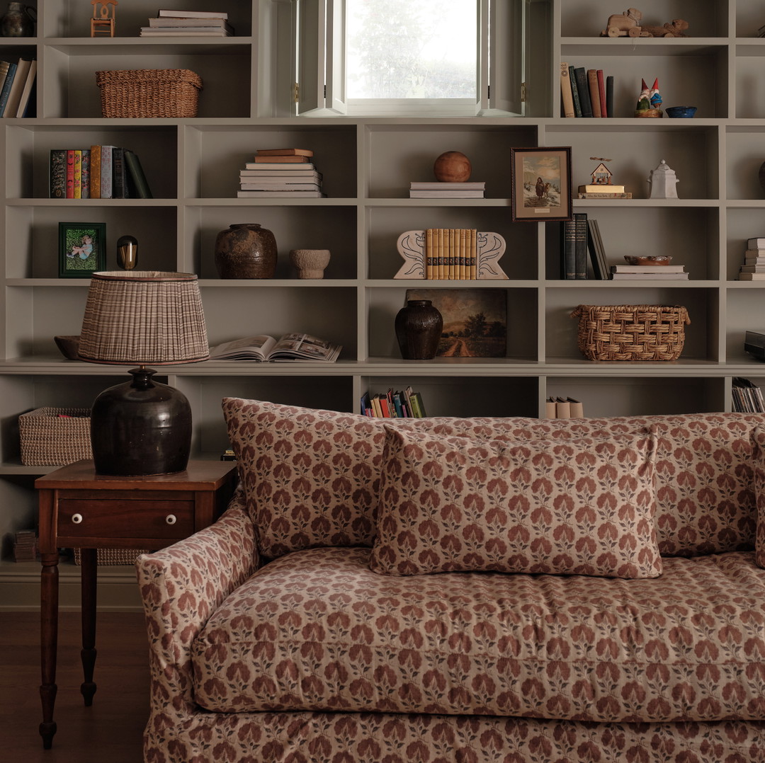 a couch sitting in front of a book shelf filled with books