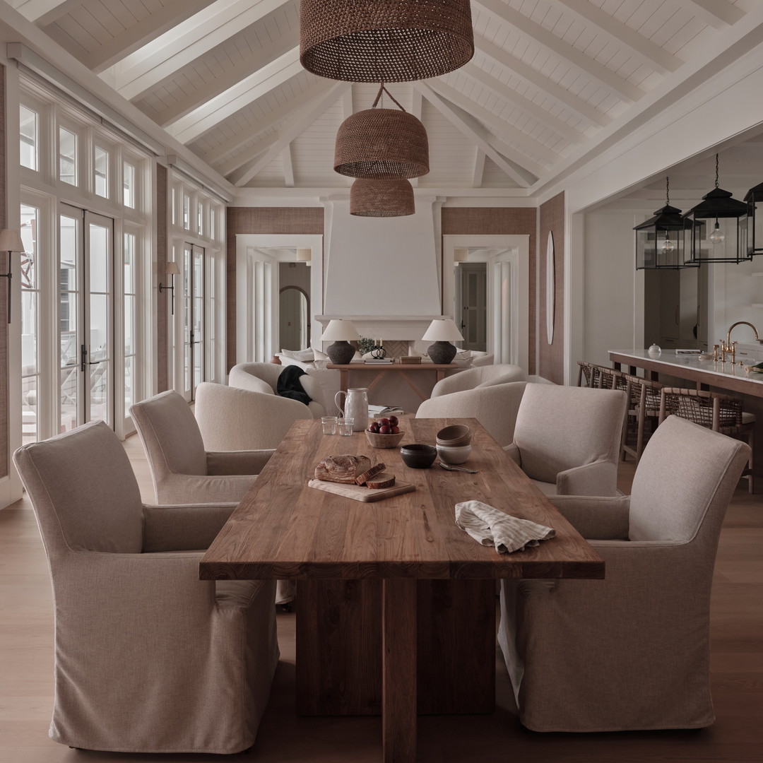 a dining room with a wooden table surrounded by white chairs