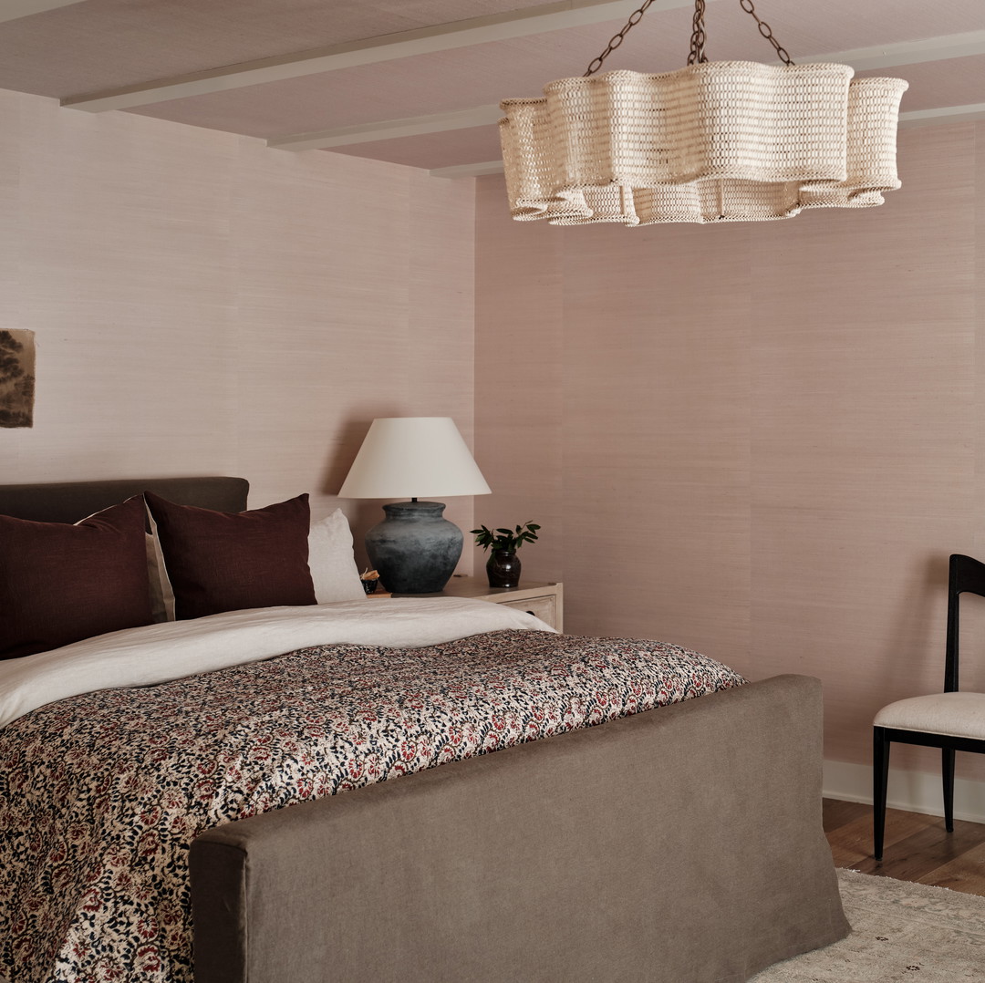 a bedroom with a bed, chair and a chandelier