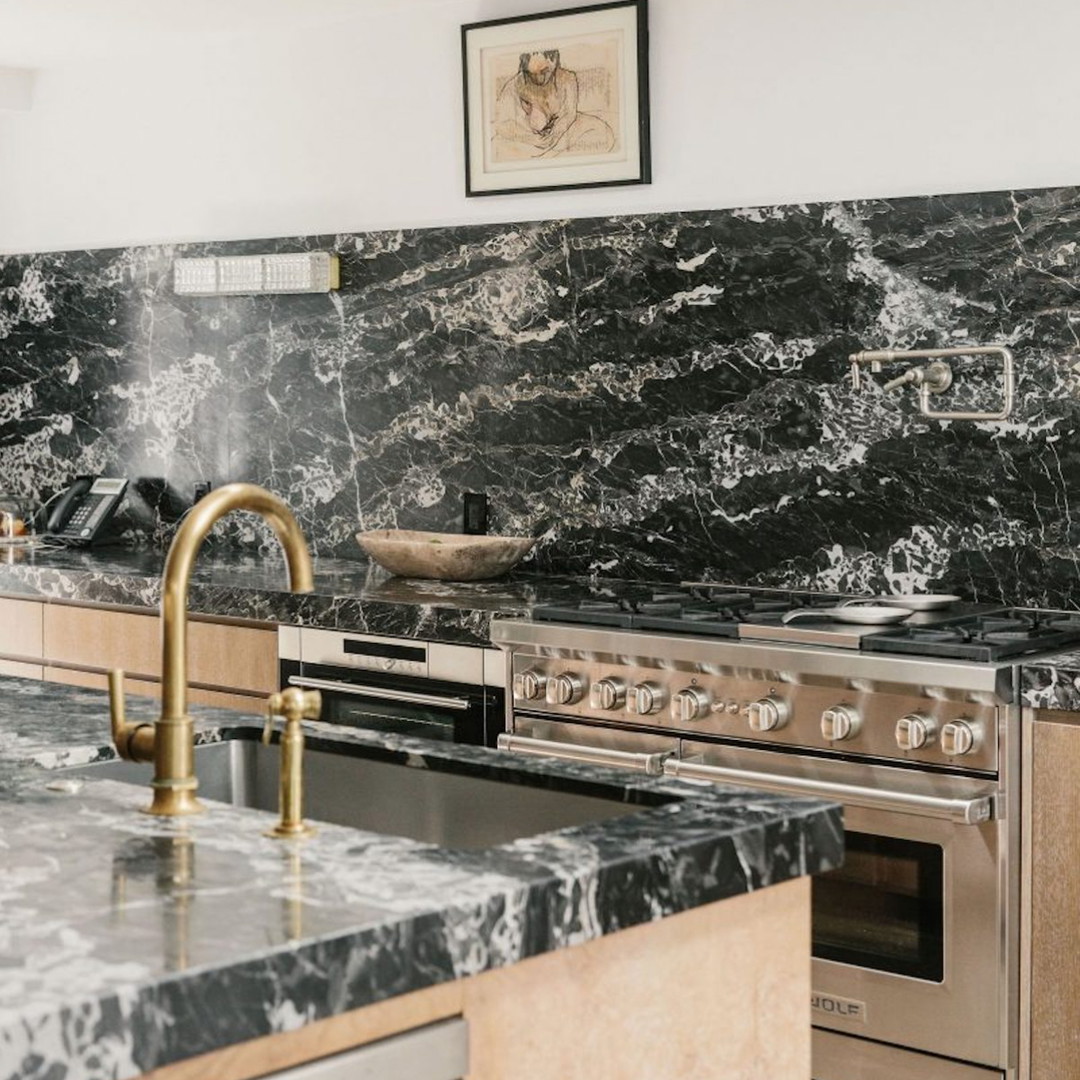 a kitchen with marble counter tops and a gold faucet