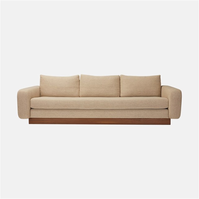 a beige couch with a wooden frame on top of it