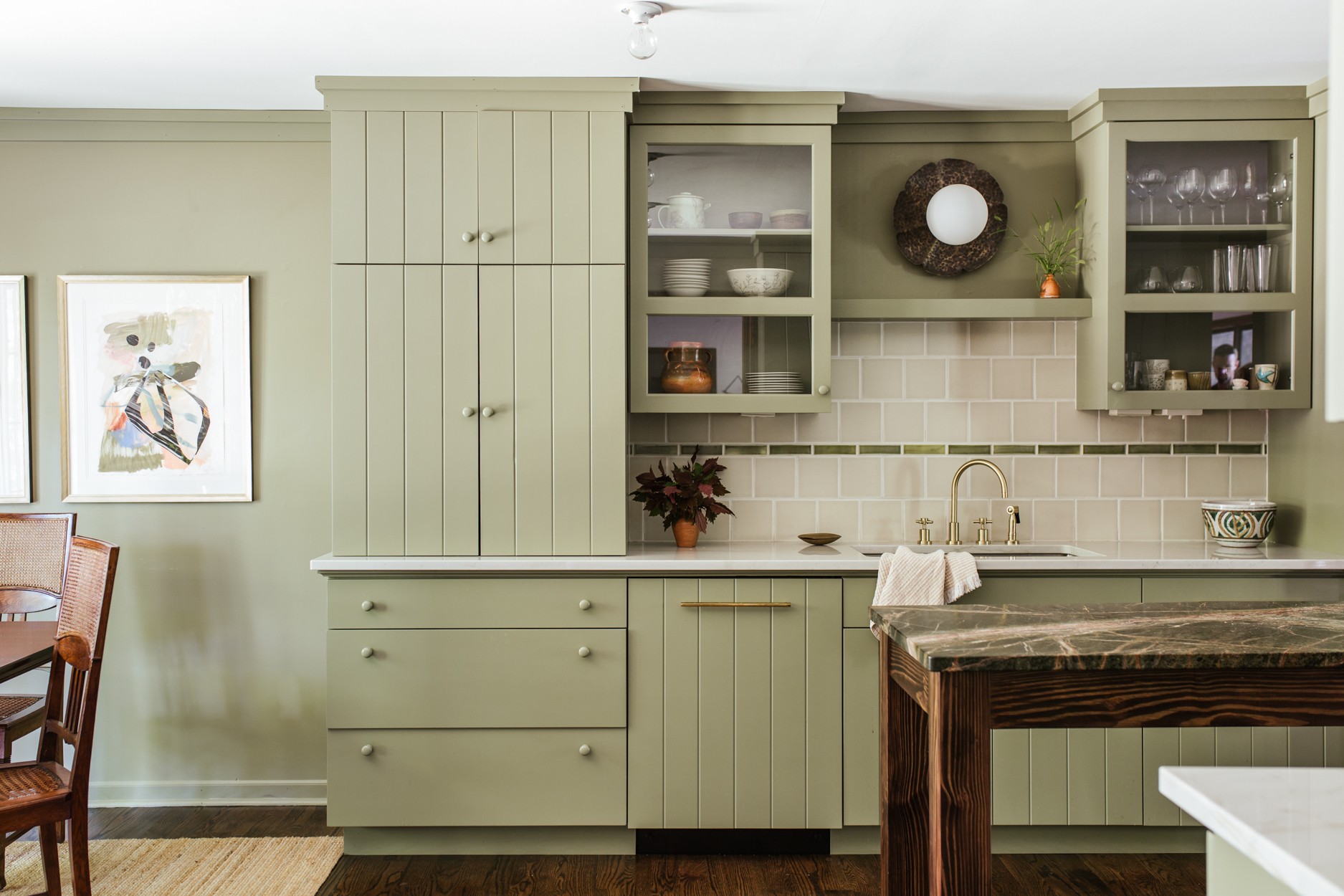 a kitchen with green cabinets and a wooden table