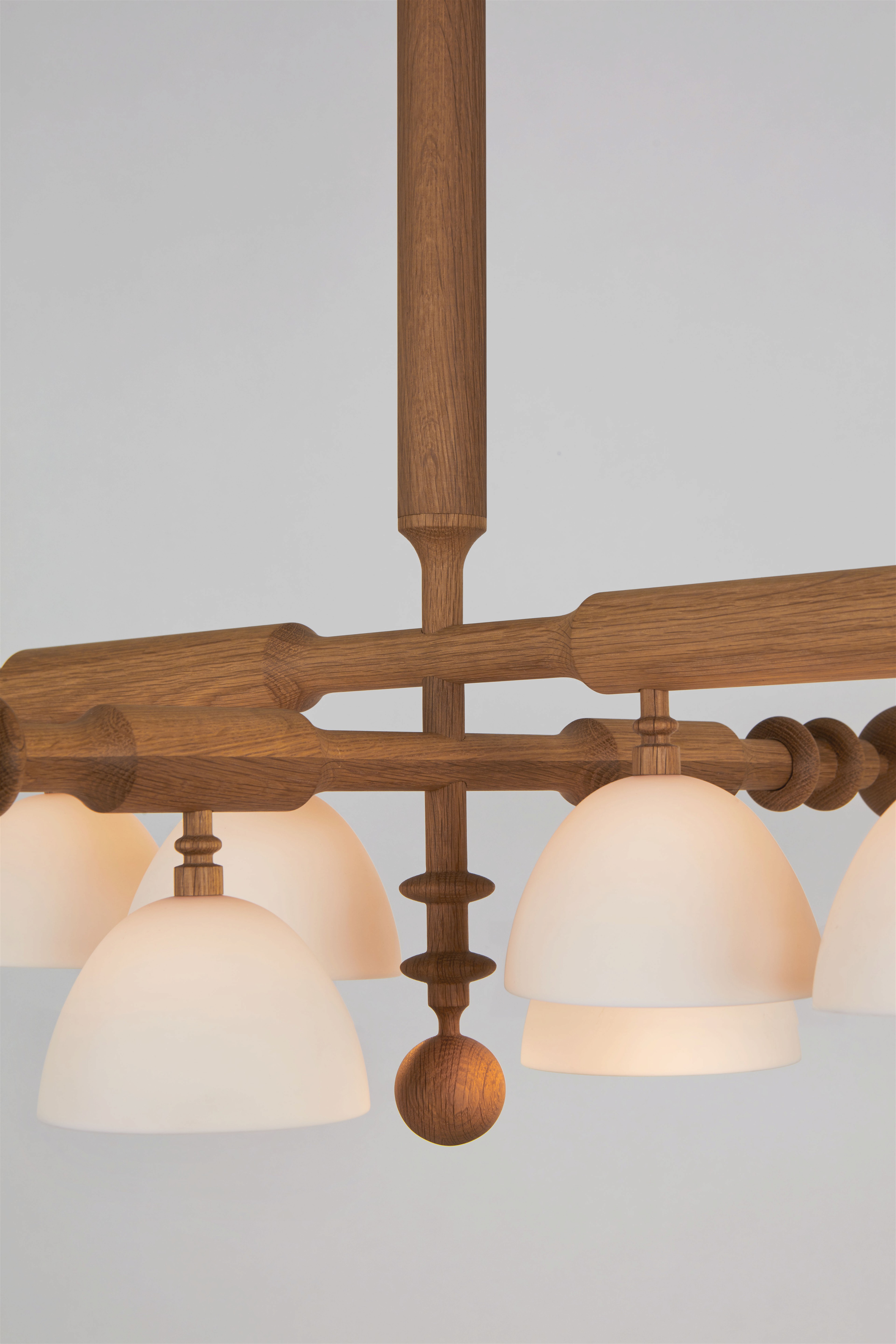 a wooden chandelier with five white glass shades