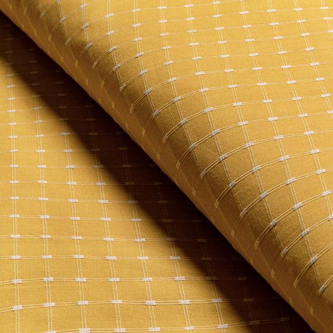 a close up of a yellow fabric with white squares