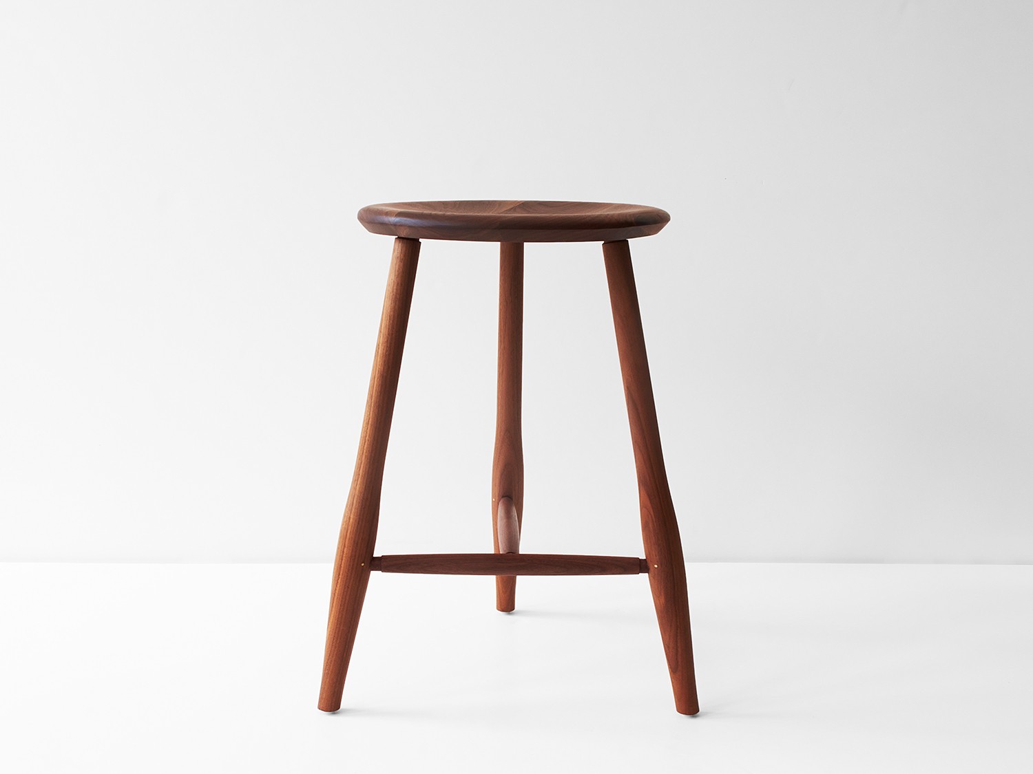 a wooden stool sitting on top of a white floor