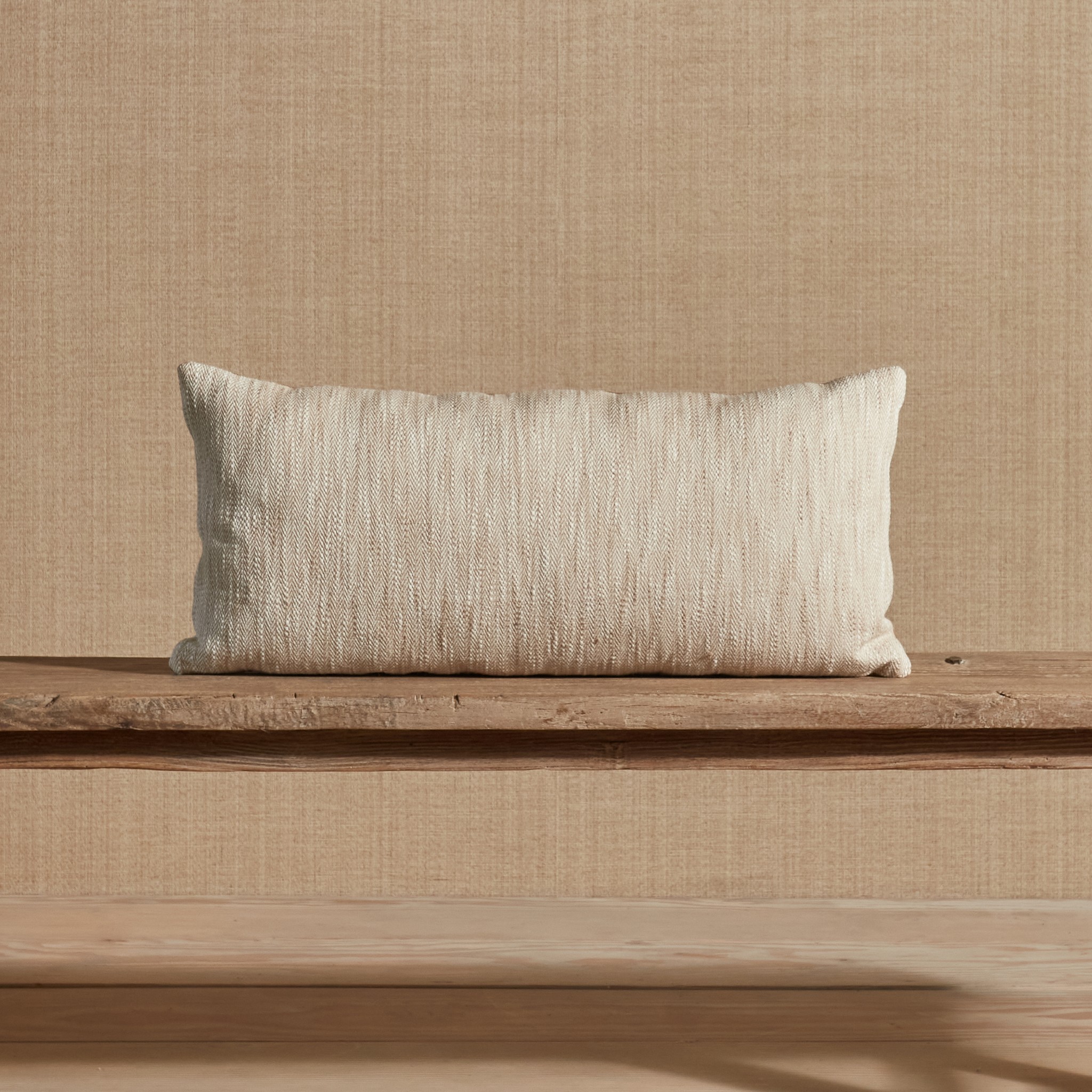 a white pillow sitting on top of a wooden bench