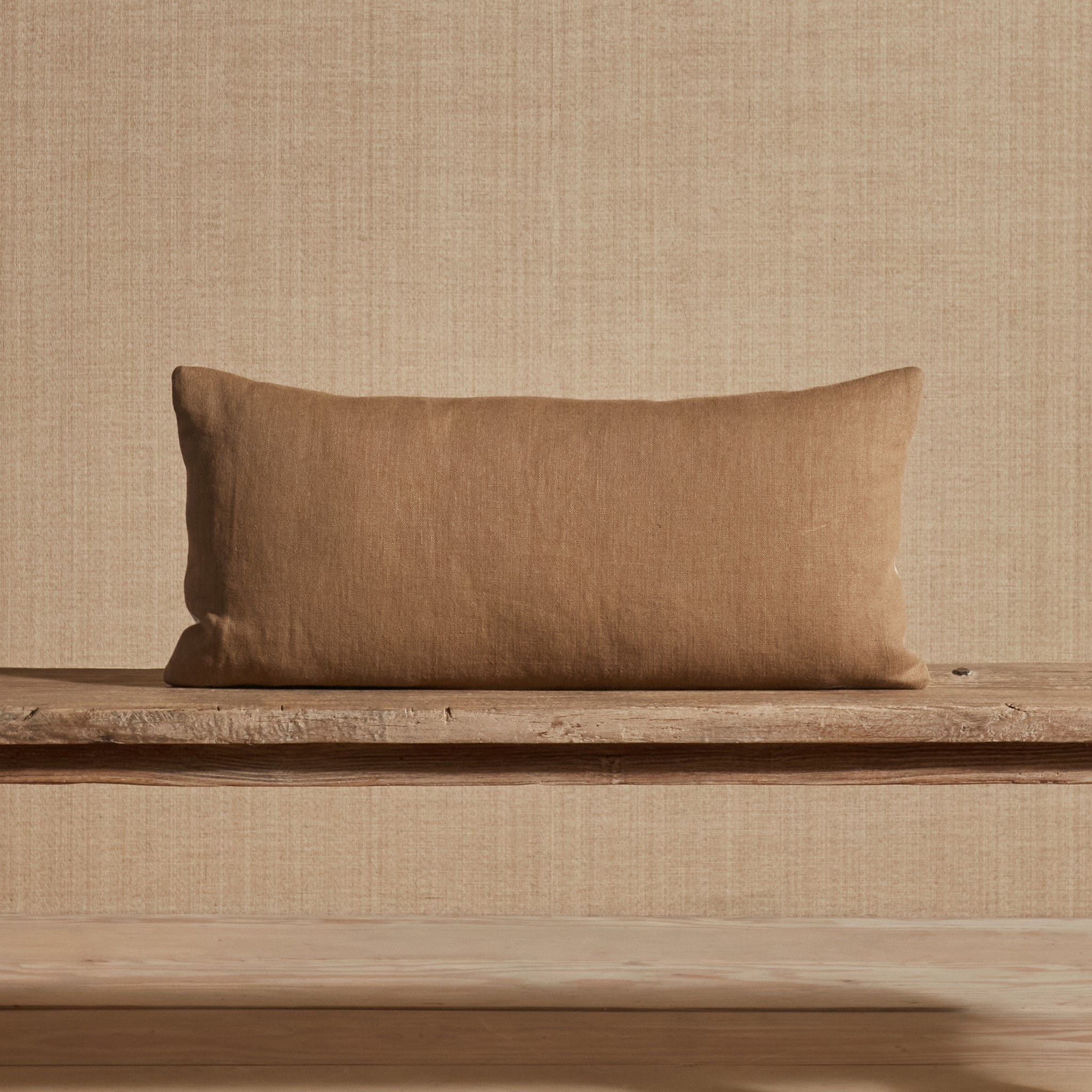 a brown pillow sitting on top of a wooden bench
