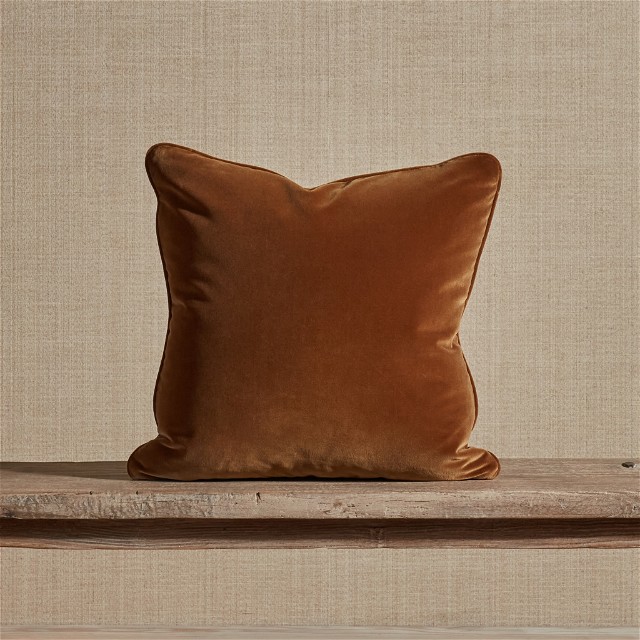 a brown pillow sitting on top of a wooden bench