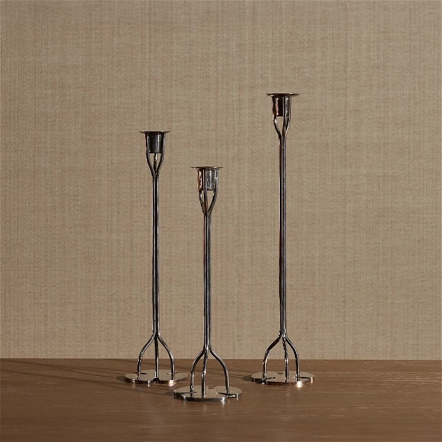a group of three metal candlesticks sitting on top of a wooden table