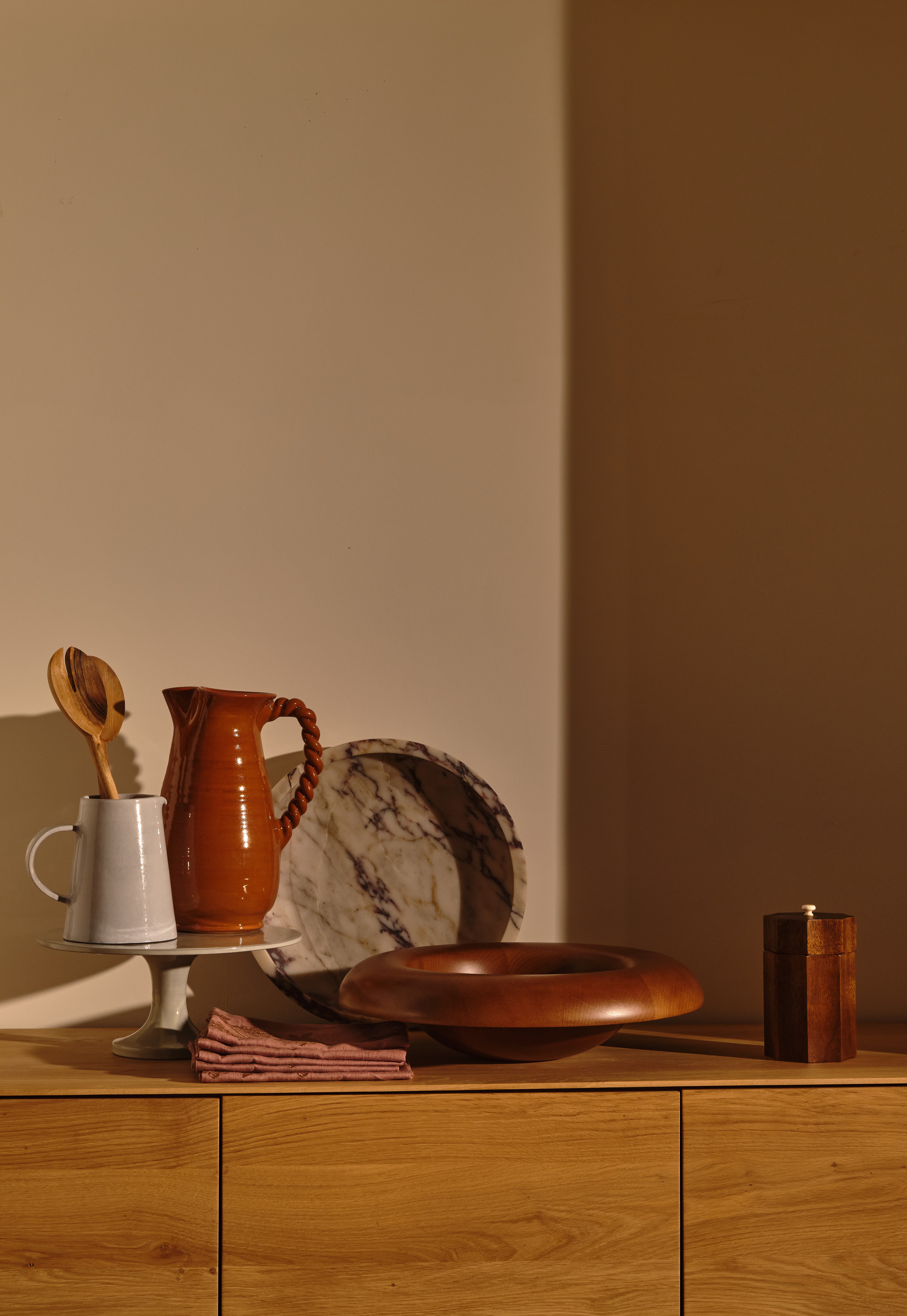a wooden dresser topped with a wooden bowl and a wooden spoon
